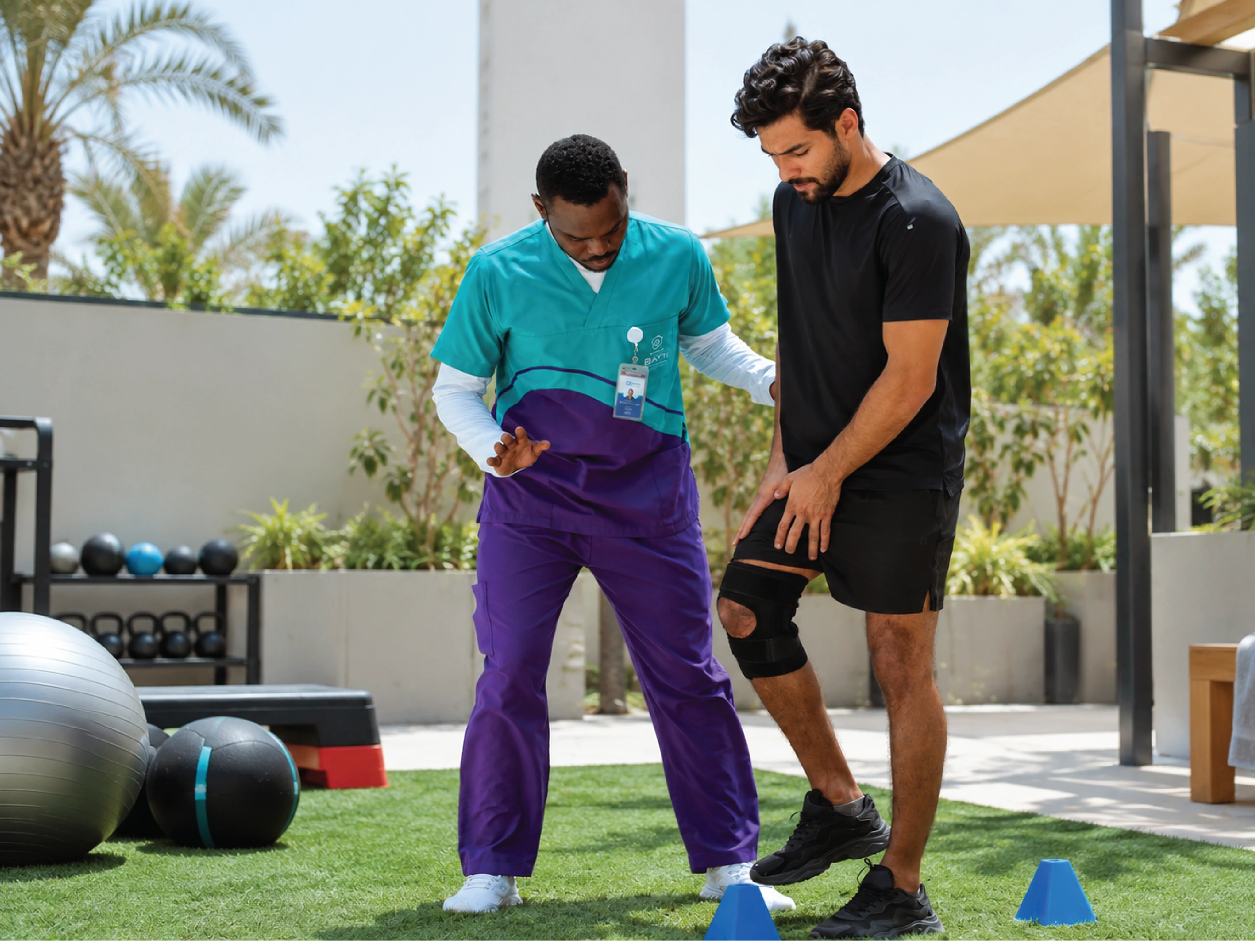 A physiotherapist coaching an adult through a resistance-band exercise on a mat